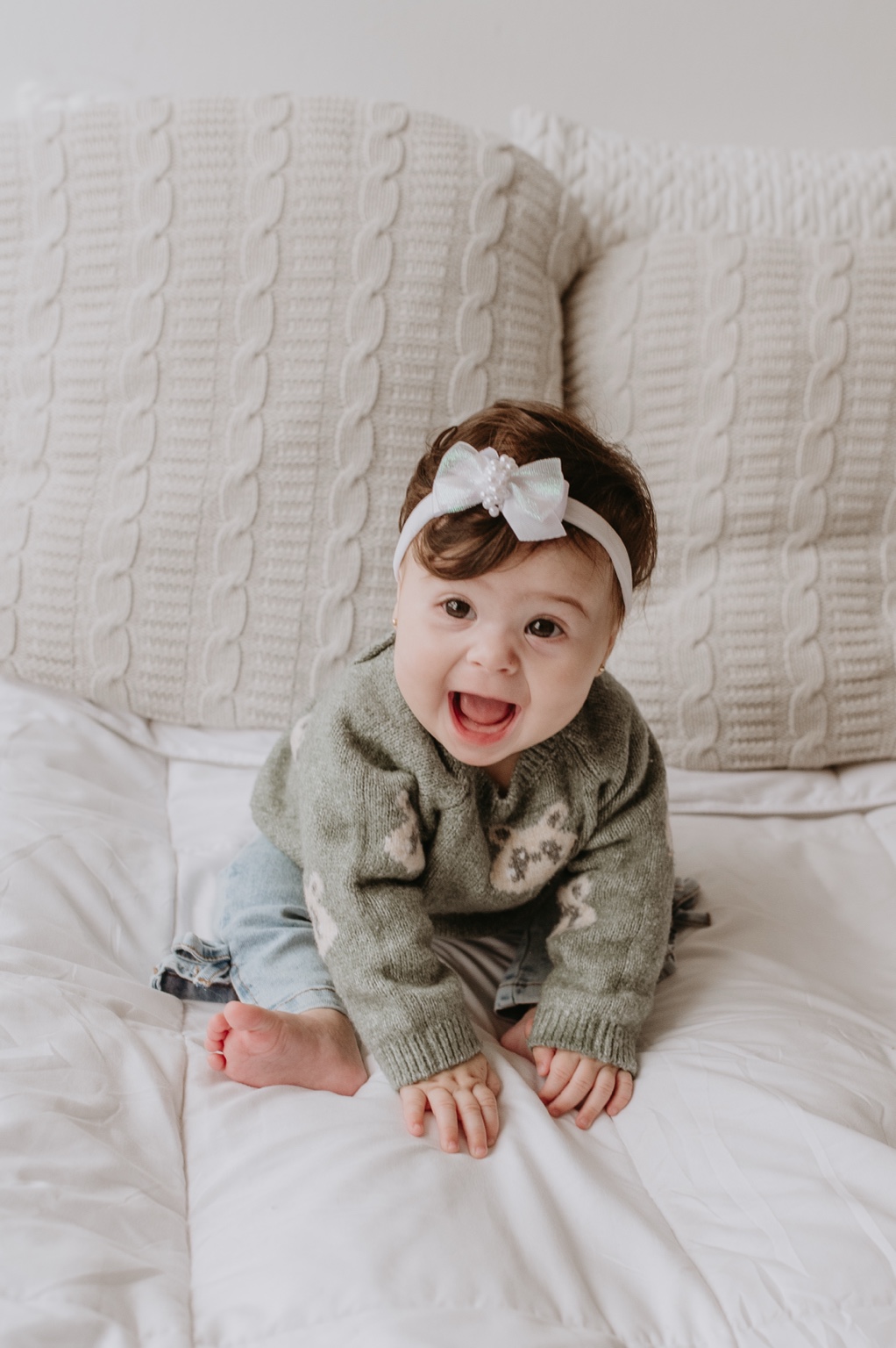 Uma das gêmeas sorrindo sentada na cama